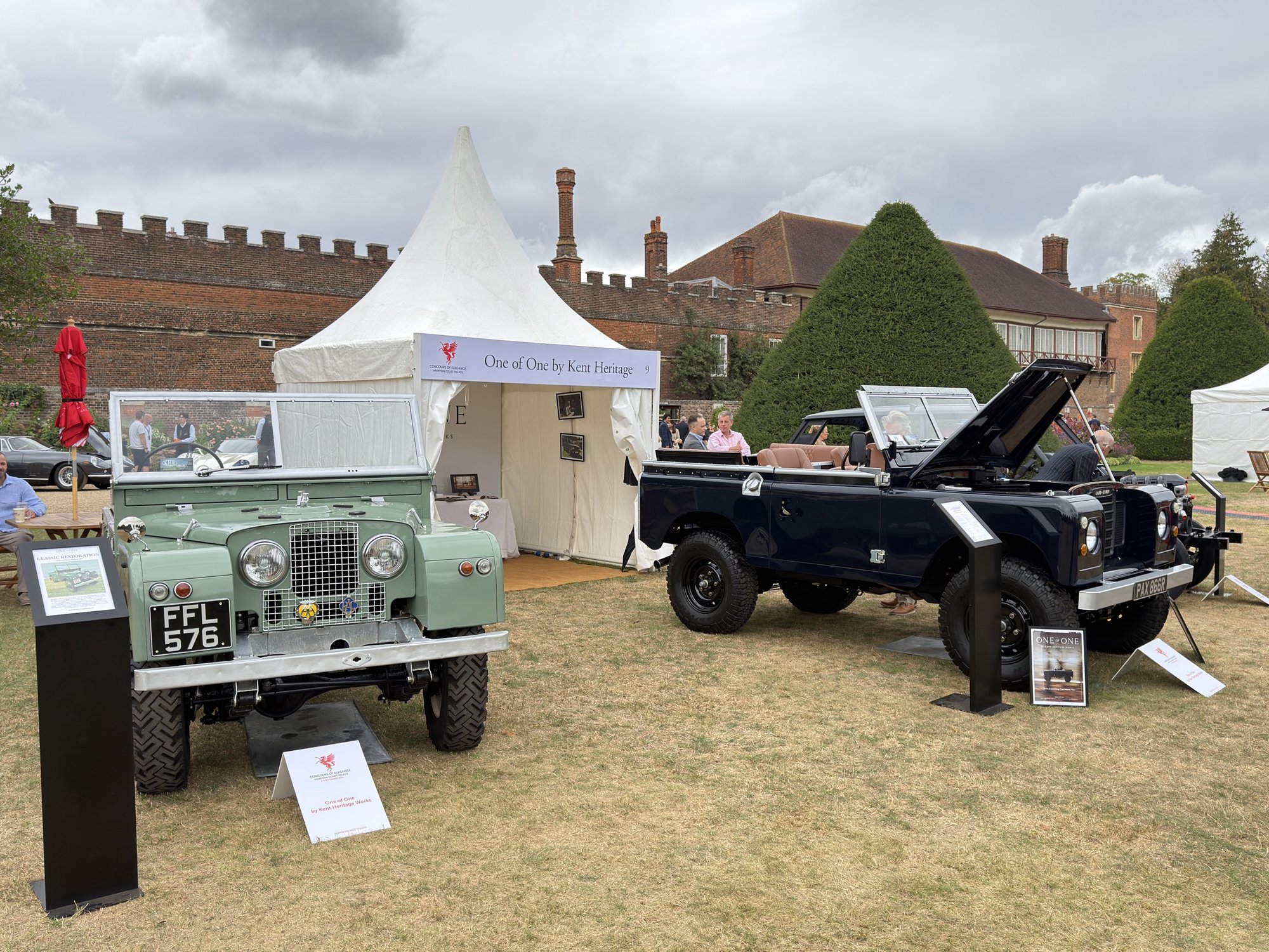 Two restored Land Rovers on the lawn in front of the One of One by Kent Heritage stand.