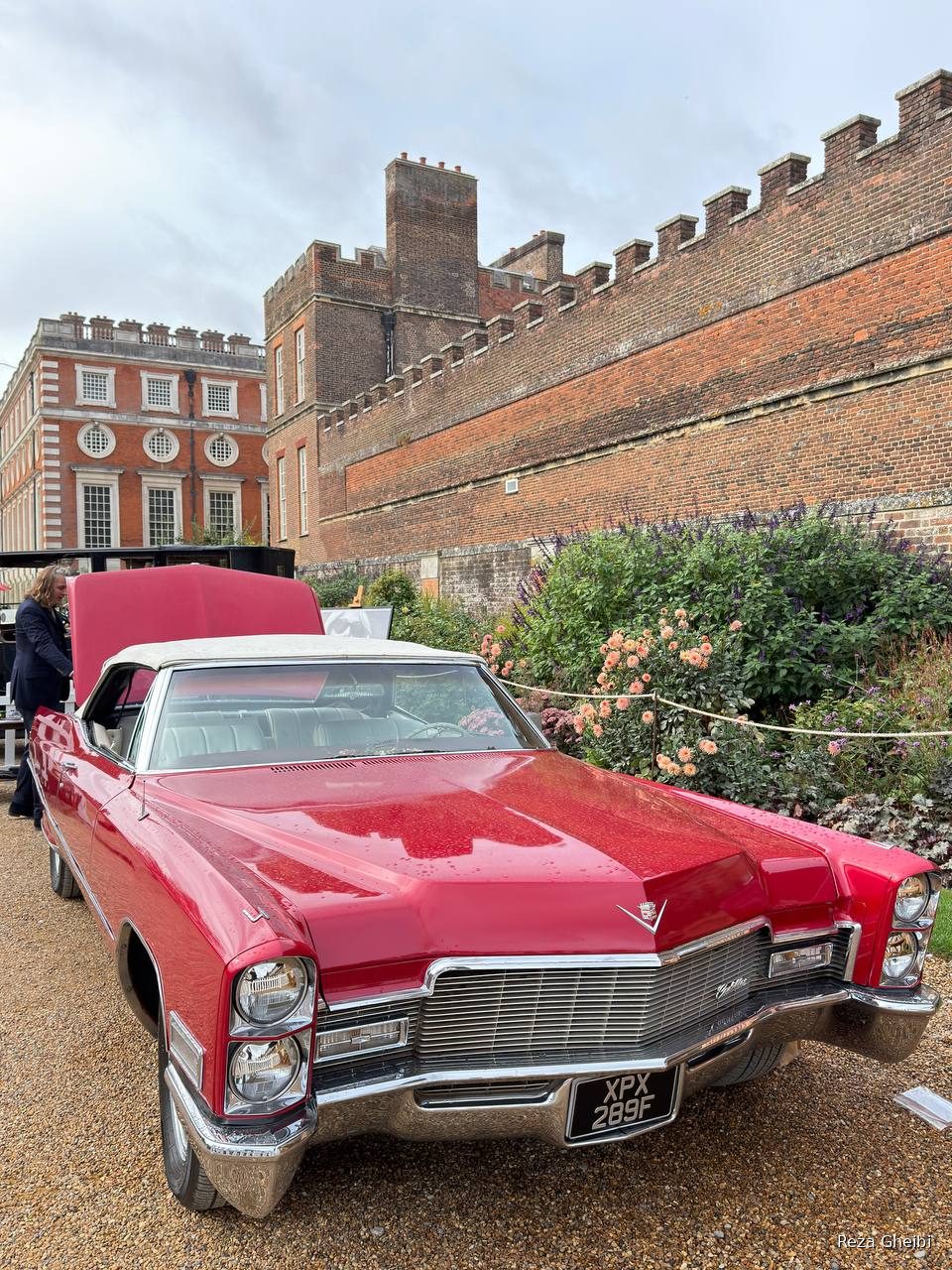 A red 1960s Cadillac convertible with a white top against the castellated palace wall.