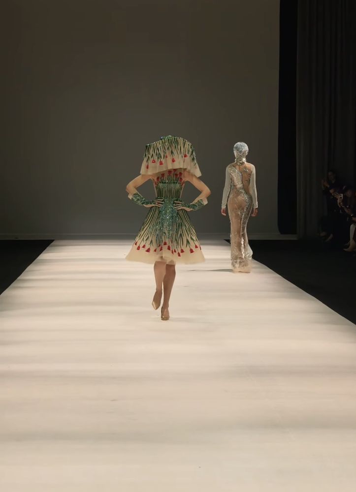 A short dress embroidered with green reeds and red tulips under a sculptural ruffled collar