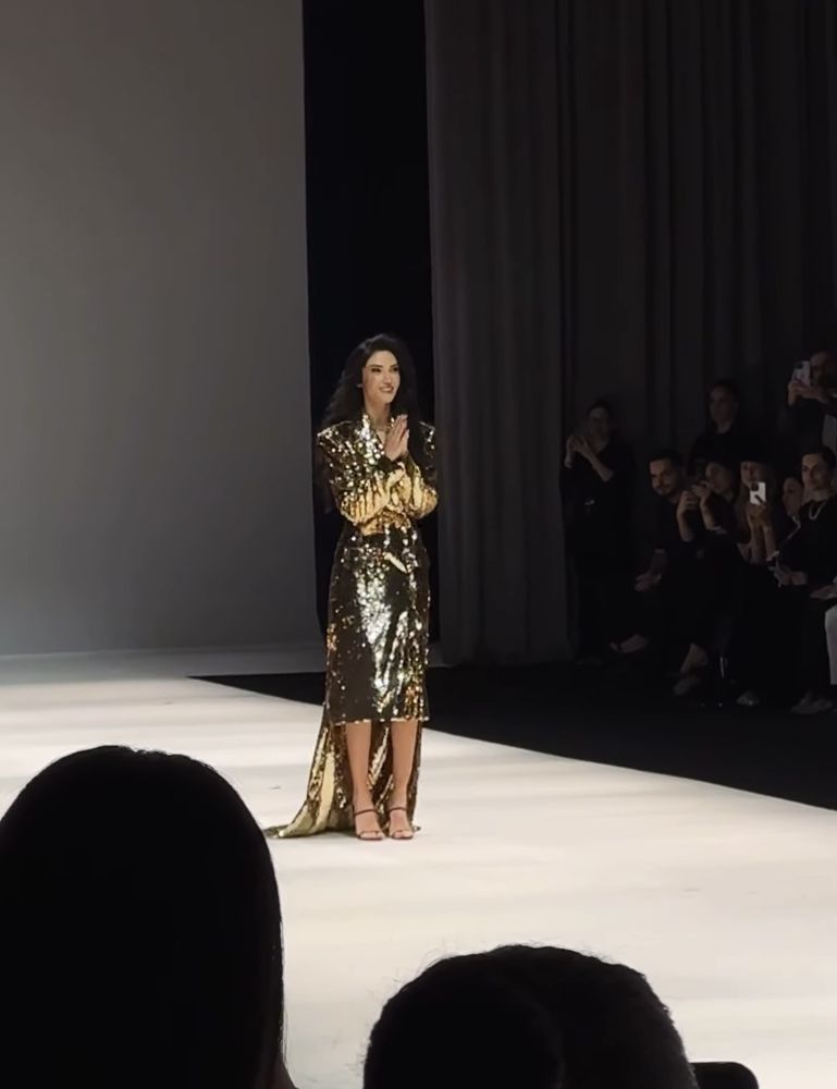 The designer taking her bow on the runway in a gold sequin dress