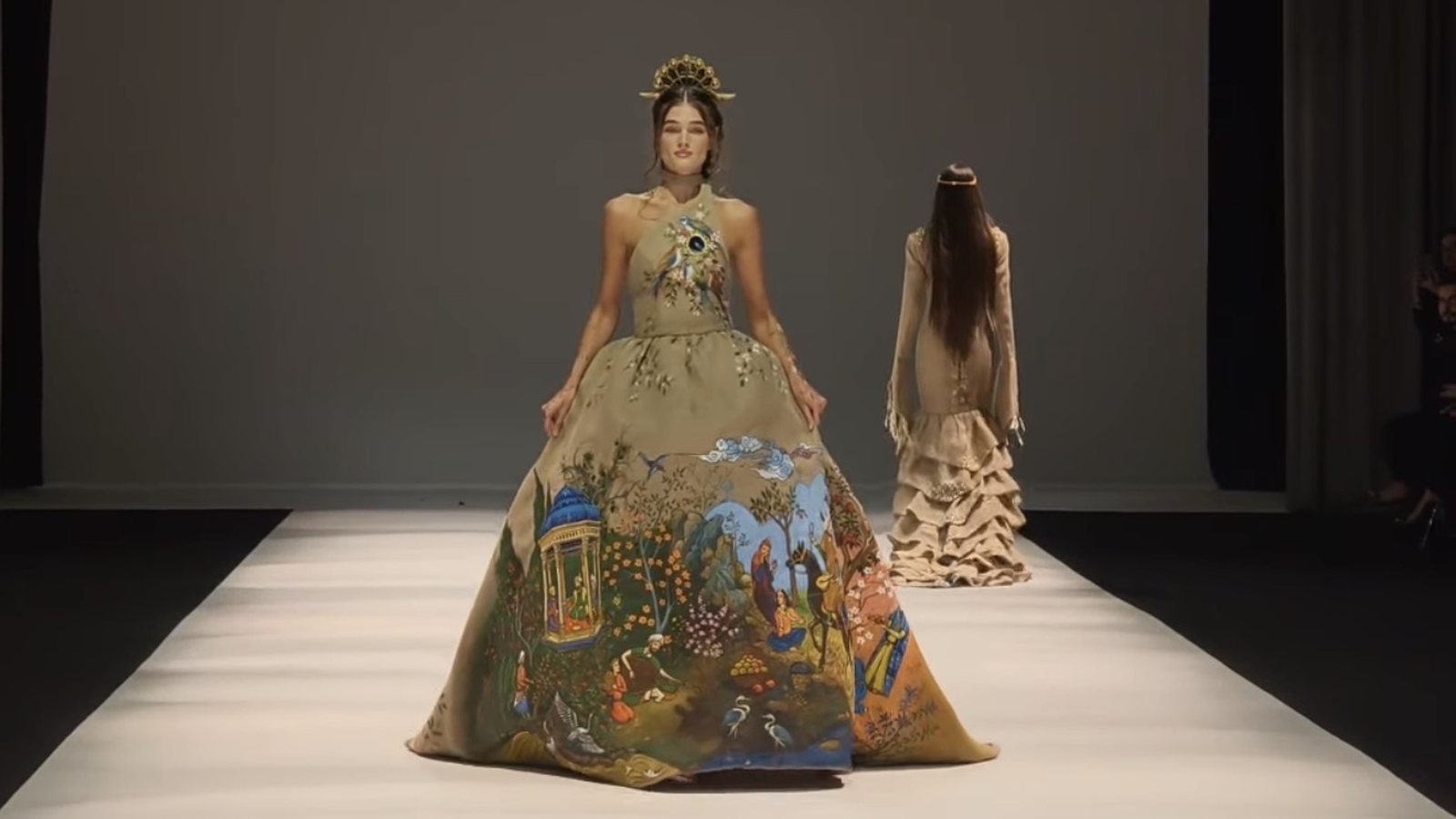 A full-skirted gown hand-painted with a Persian garden, worn with a gold crown, on the Dubai Fashion Week runway