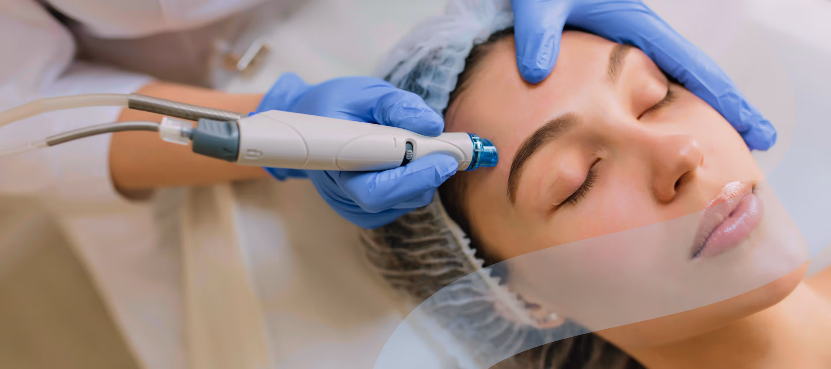 Woman receiving facial treatment with a microdermabrasion device by a professional wearing blue gloves.