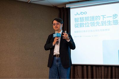 一位男子在演講，背景投影顯示智慧照護相關中文簡報。
