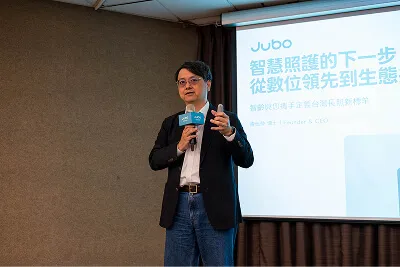 一位男子在演講，背景投影顯示智慧照護相關中文簡報。