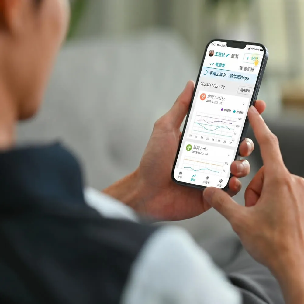 一個人用手機查看健康app,顯示血壓和心率的趨勢圖表。