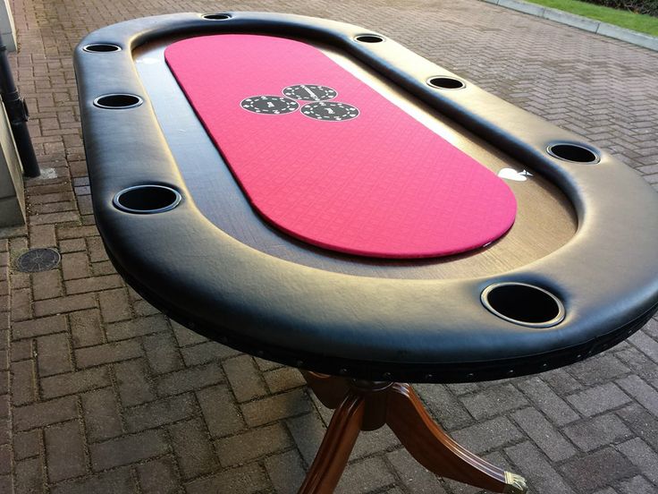 This may contain: a pink and black surfboard sitting on top of a wooden stand next to a brick sidewalk