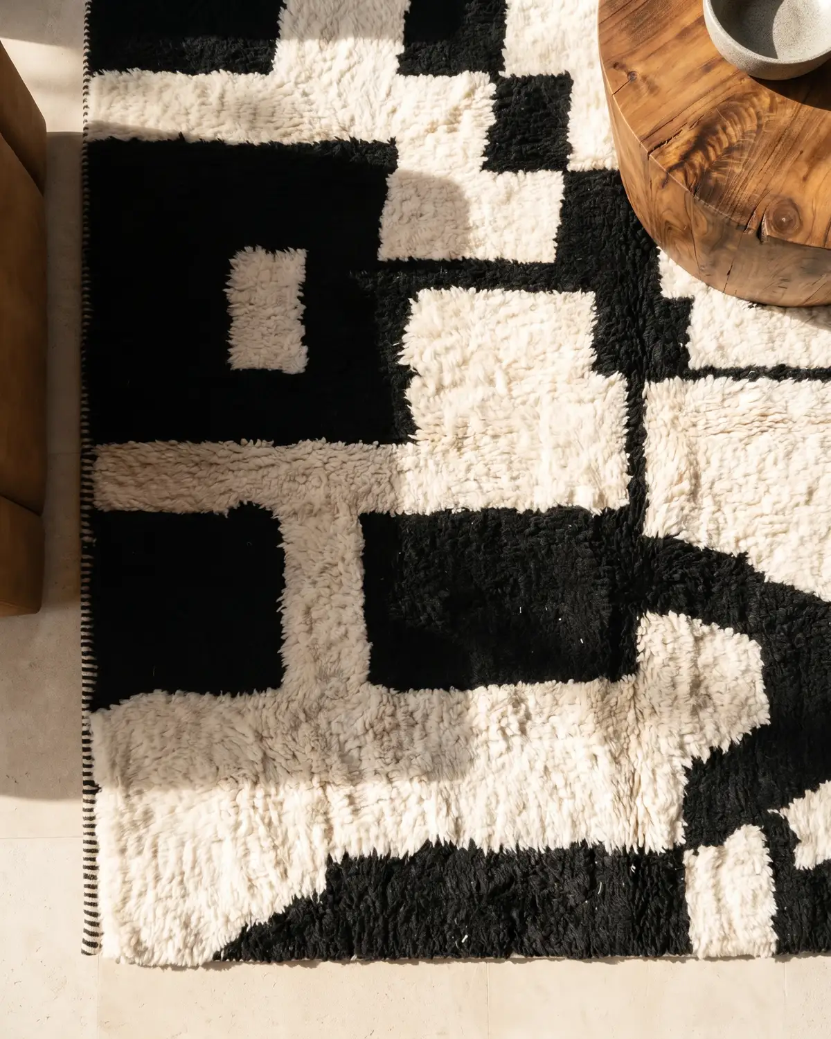 Agatha black and white geometric Moroccan rug – overhead detail of bold block pattern with round wood coffee table