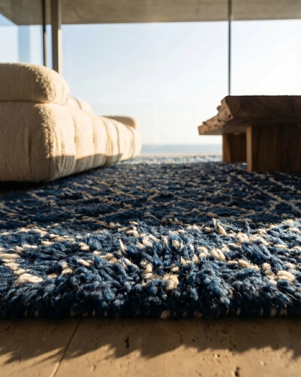 Azura indigo Moroccan rug – ground-level close-up of dense blue wool texture with ocean view and white sofa