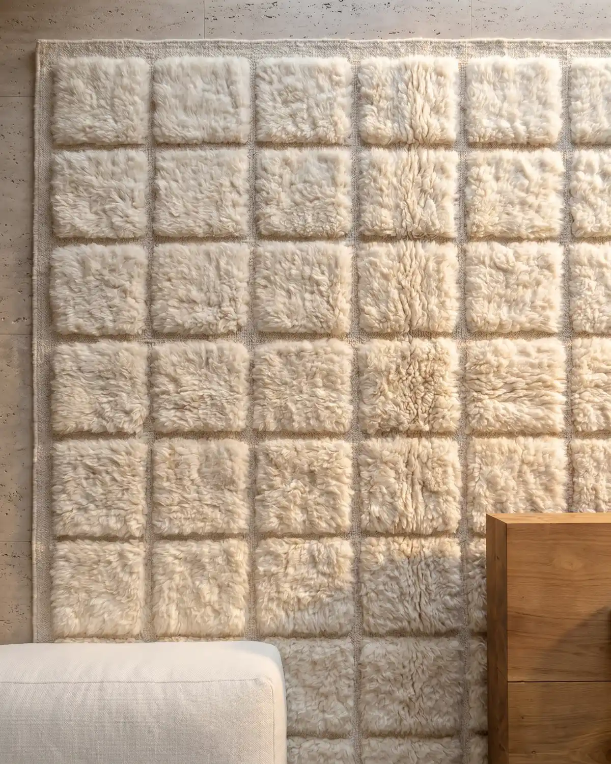 Claranis white square-grid Moroccan rug – full overhead view of fluffy wool tile pattern against travertine wall