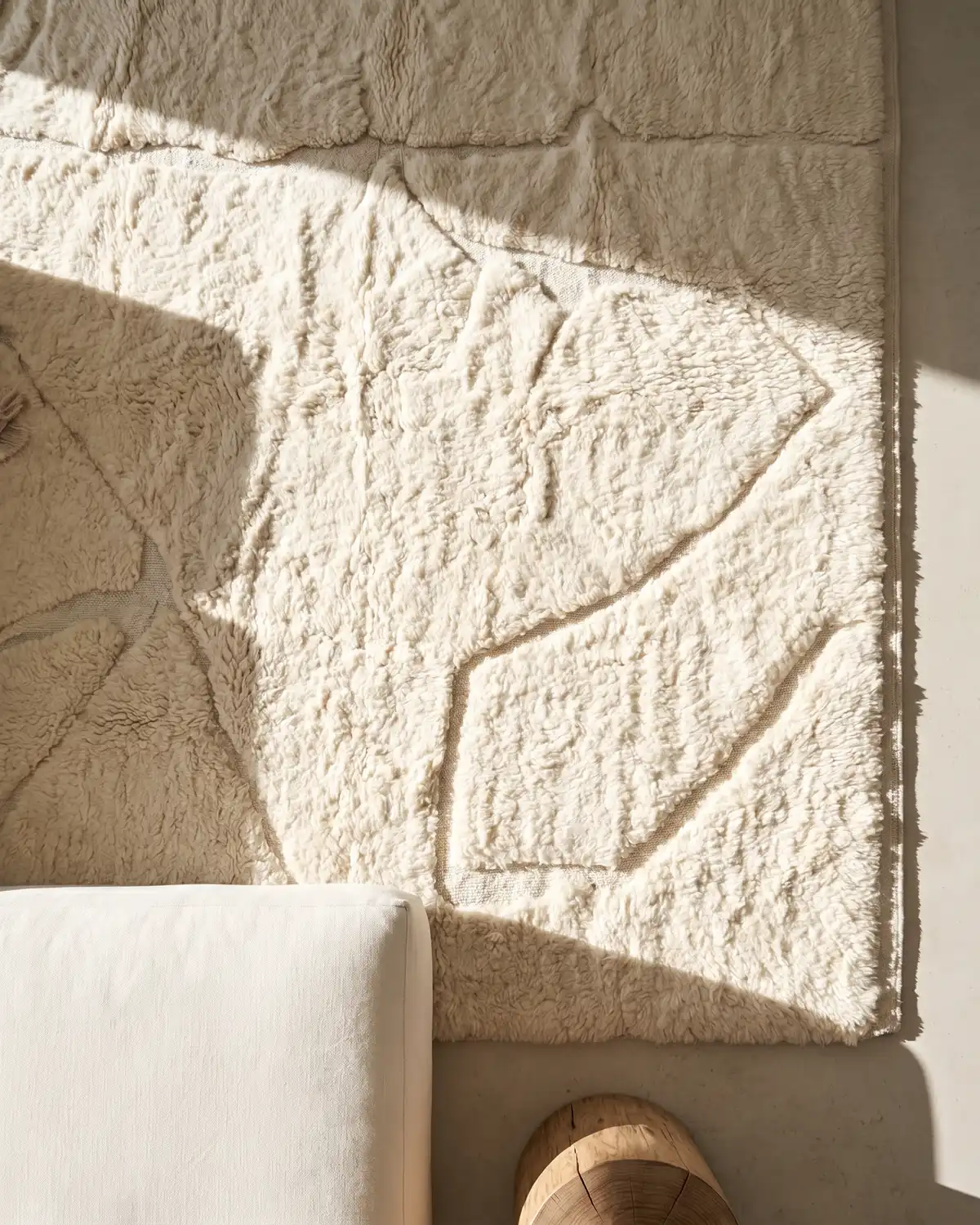 Coco fluffy white Moroccan rug – detail of organic relief pattern with natural light and white sofa
