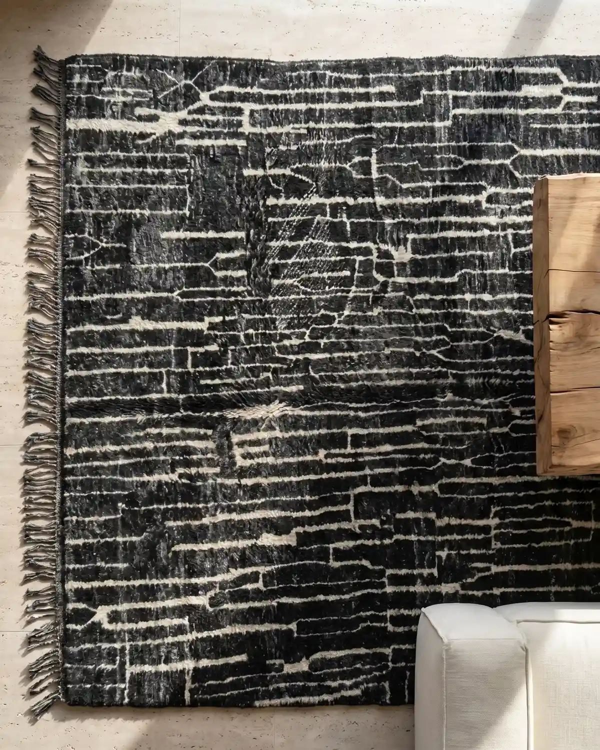 Hector dark charcoal Moroccan rug – overhead view of organic white line pattern with fringe and wood side table