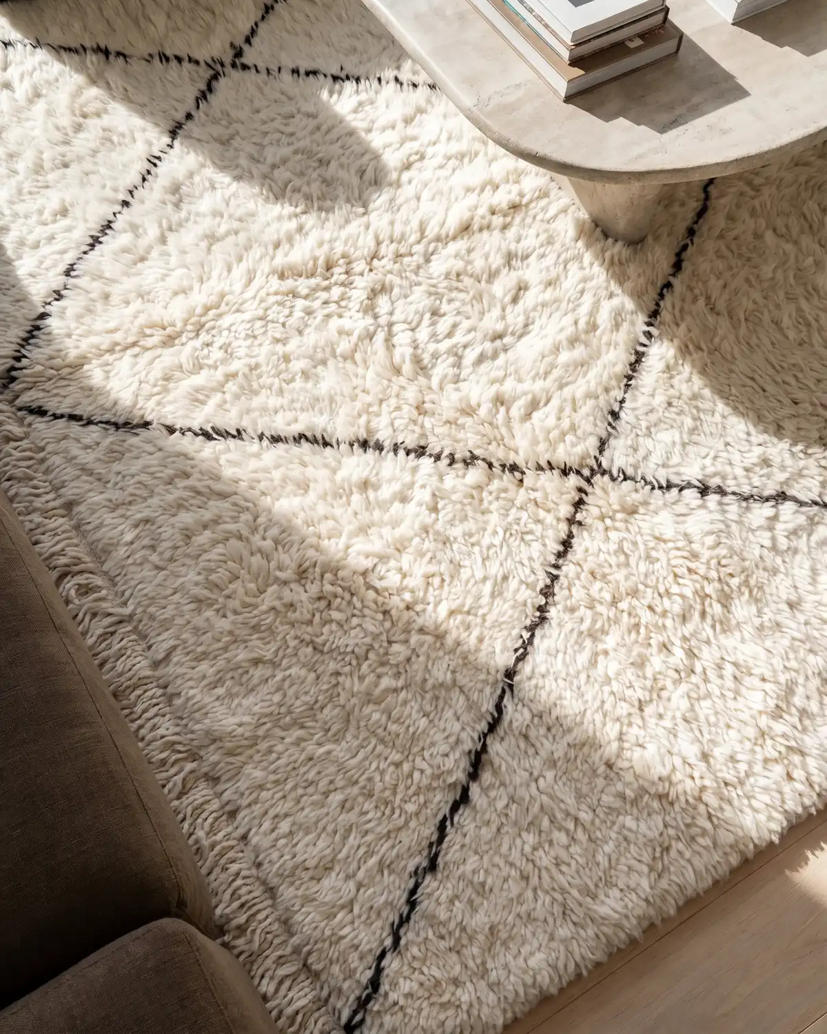 Melo Beni Ourain rug – overhead detail of fine black diamond lines on fluffy ivory wool with travertine coffee table