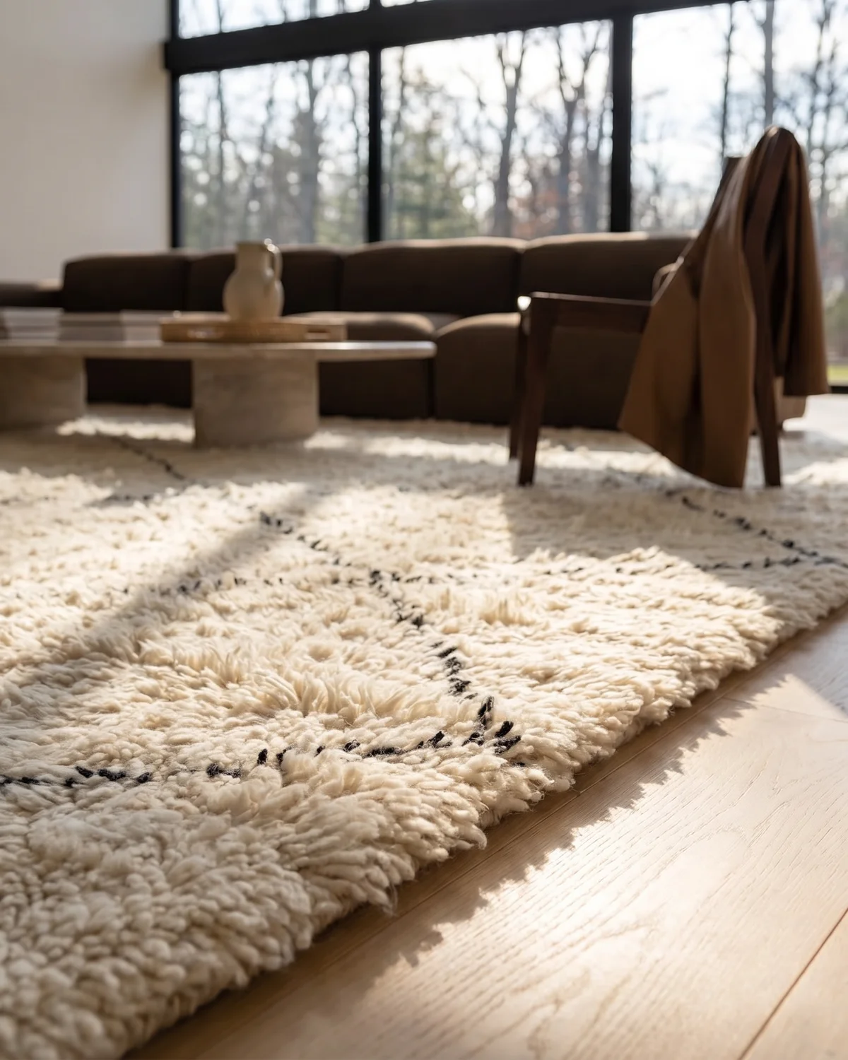 Melo fluffy white diamond Moroccan rug – ground-level close-up of dense ivory wool and black line pattern in a forest-view living room