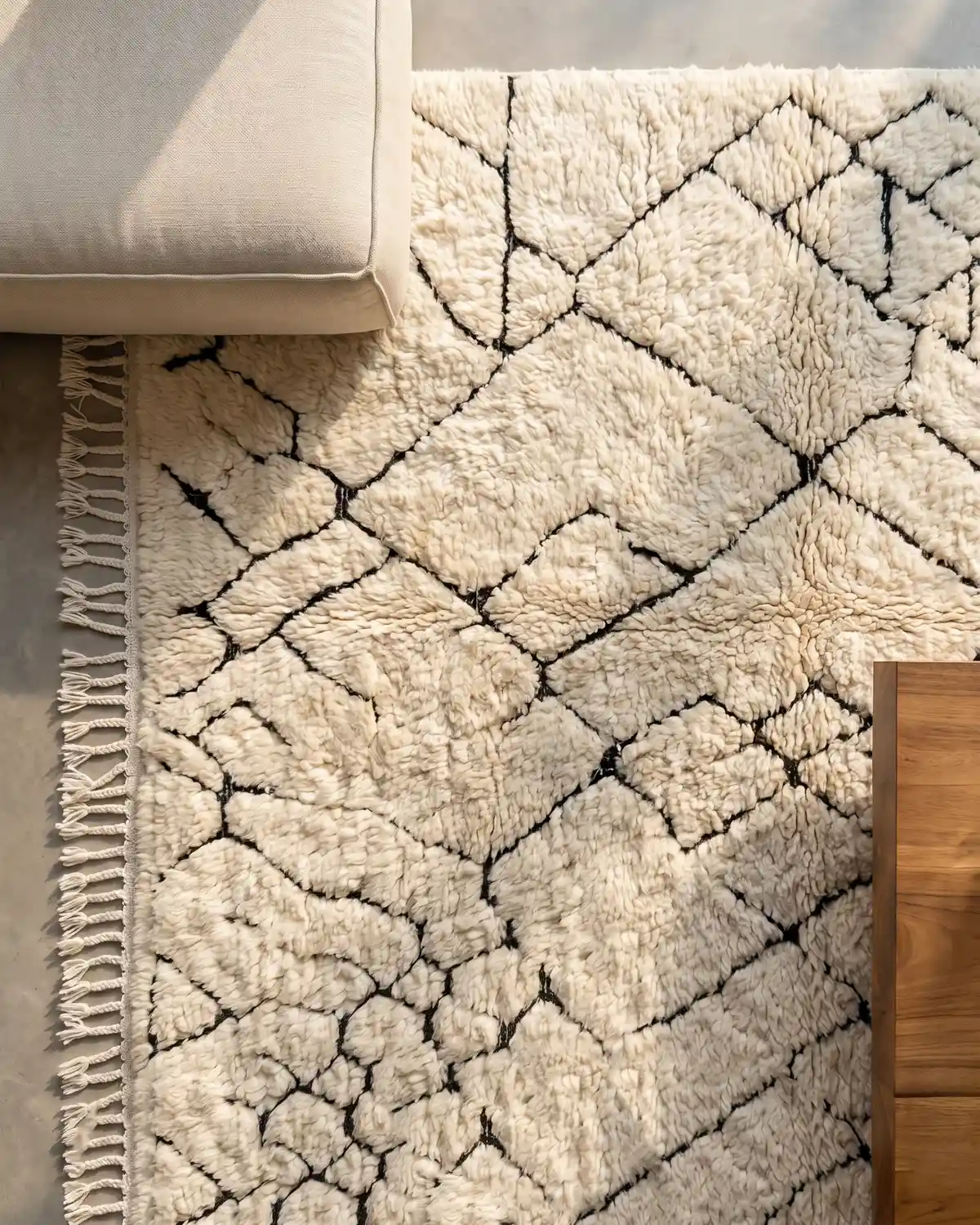 Velunithia abstract black and white Moroccan rug – overhead detail of organic cell pattern and fringe with linen sofa and wood side table