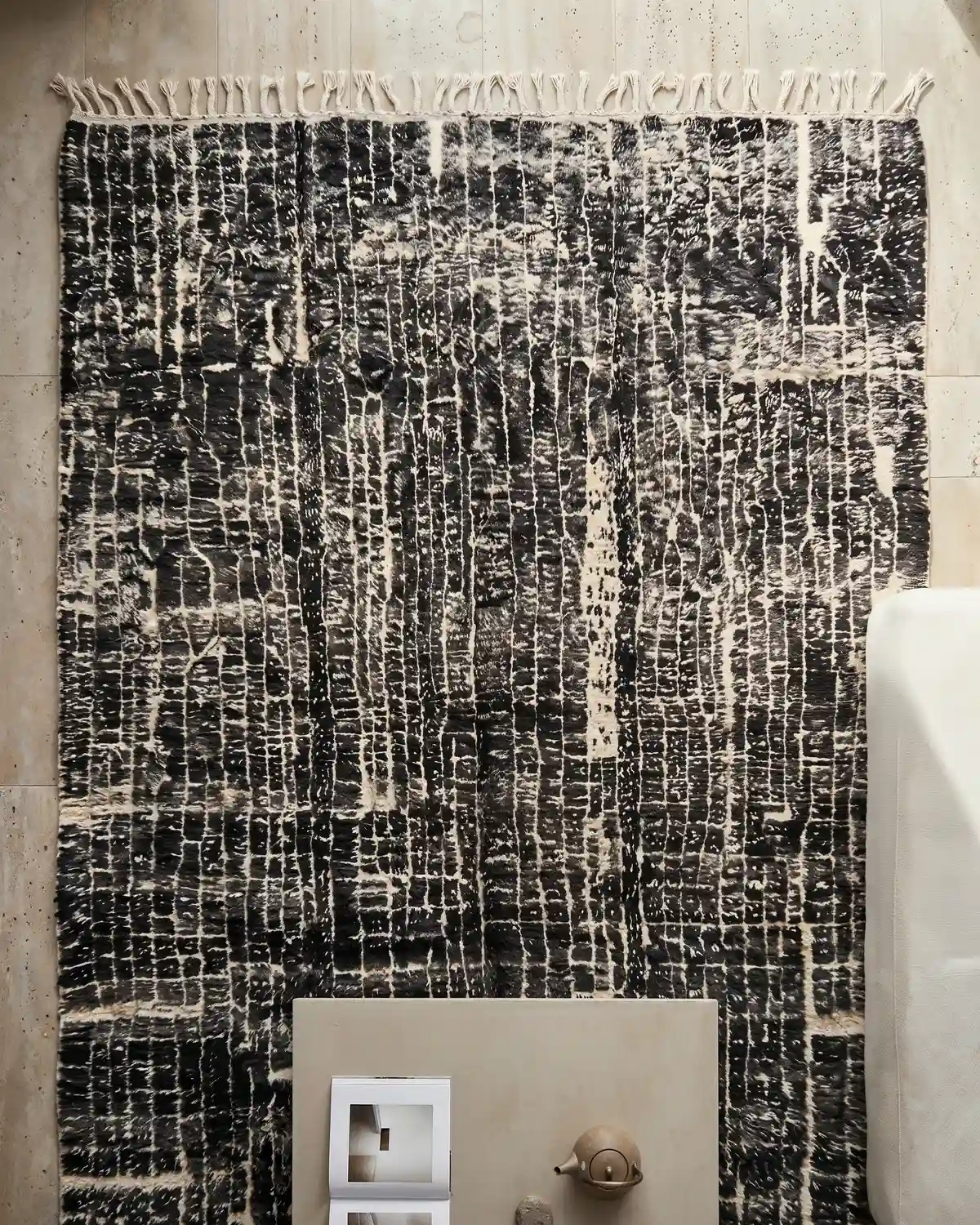 Hector handwoven rug detail – close-up of black and ivory wool texture with knotted fringe in a warm timber interior