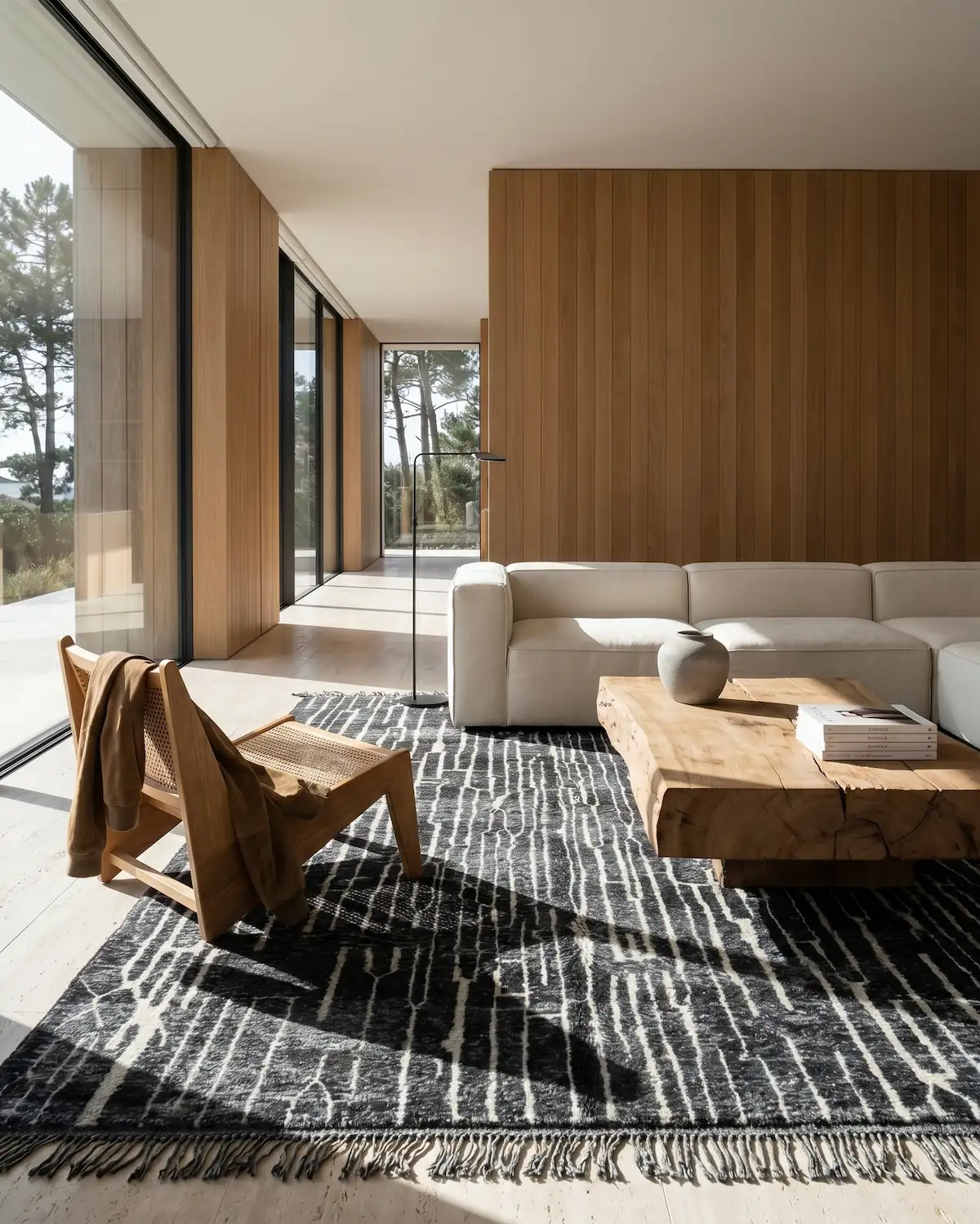 Hector dark abstract Moroccan rug – full interior view with white modular sofa, rattan chair and wood coffee table