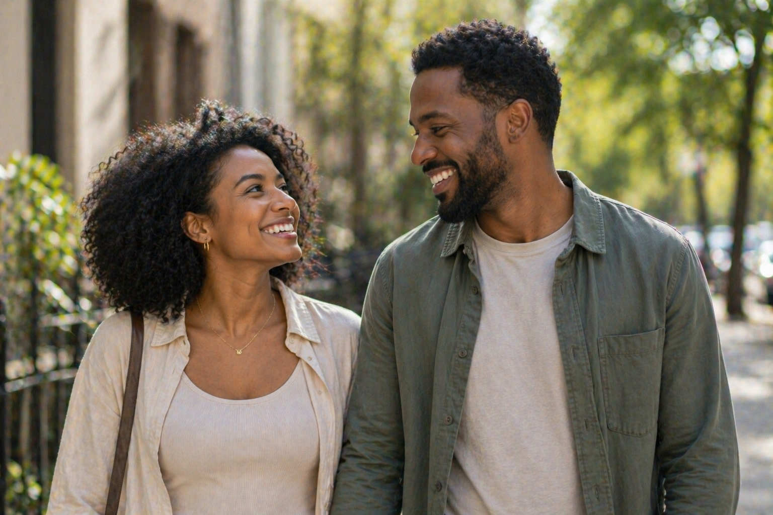 Smiling young couple walking outside on a sunny day, looking at each other.