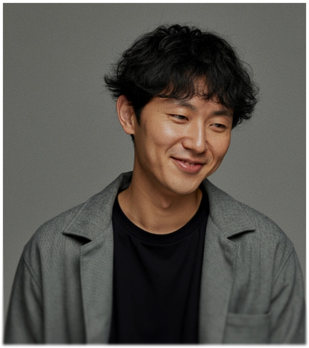 Smiling man with curly black hair in a gray jacket