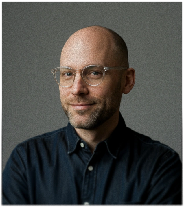 Portrait of a bald man with glasses in a denim shirt