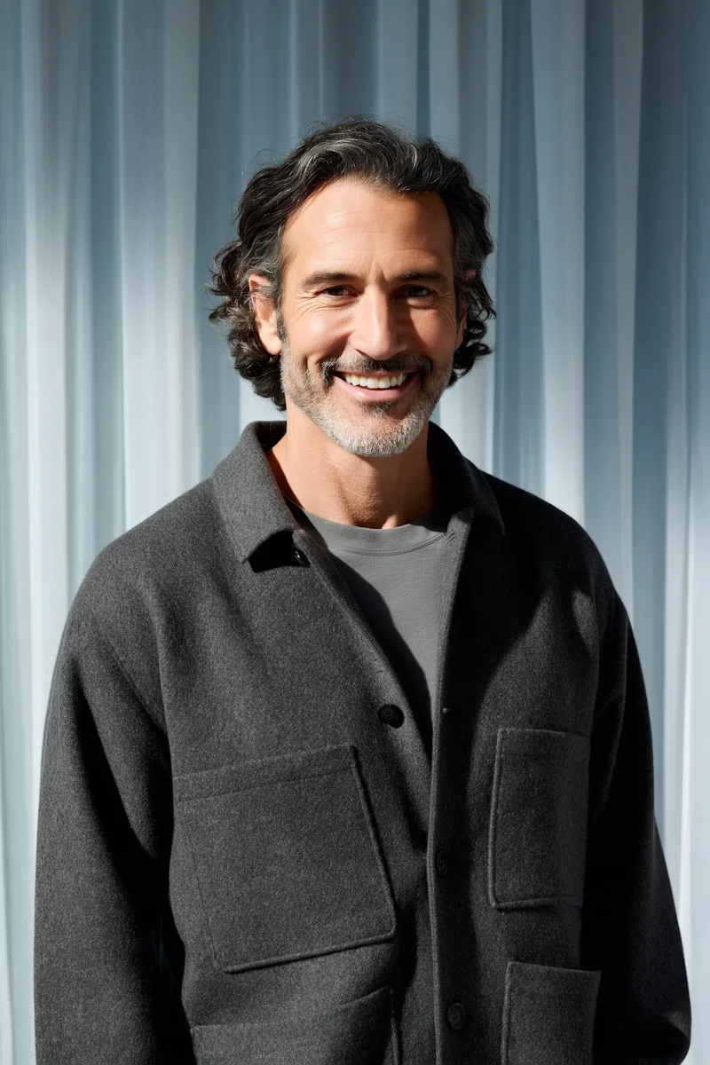 Smiling man with a gray beard in a charcoal jacket