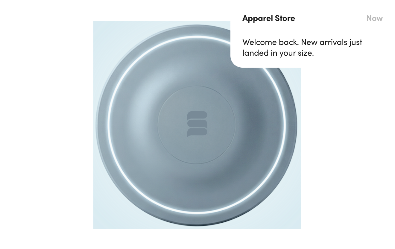 Top view of a round, metallic smart home device with a glowing circular light and a logo at the center.