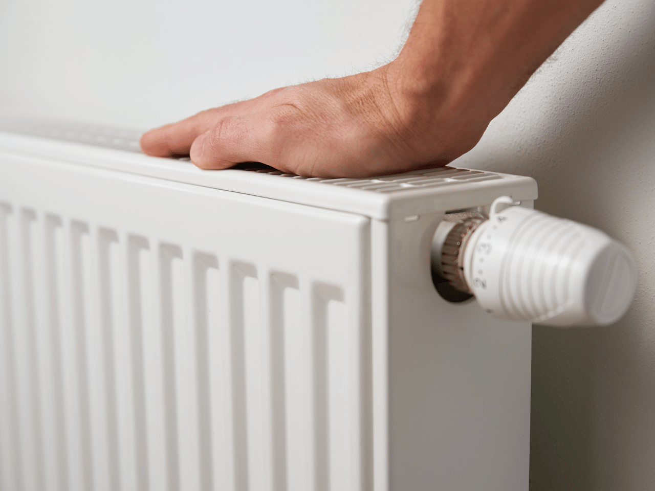 Heizung Hamburg mit Hand am Heizkörper und Thermostat
