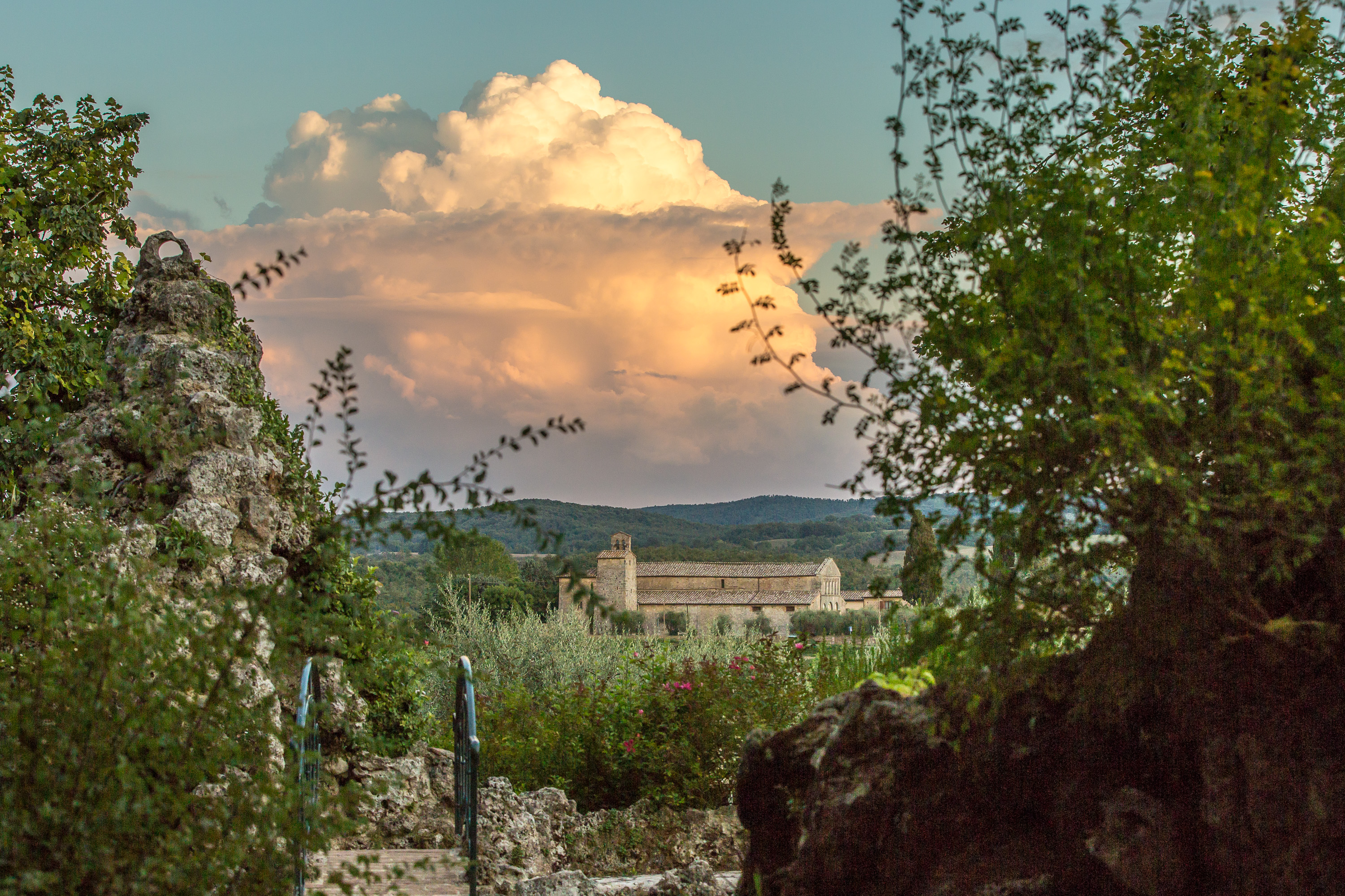 Romantic Tuscan countryside view with historic stone chapel and dramatic sunset clouds near Castello Higo luxury yoga and Pilates retreat in Italy