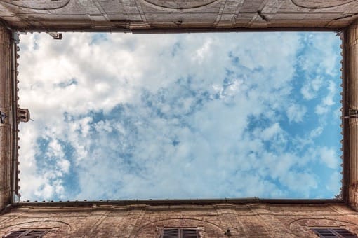 View of blue sky framed by historic Tuscan architecture at Castello Higo, a luxury yoga and Pilates retreat center in Italy