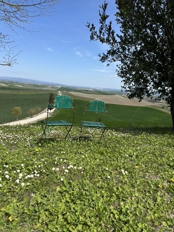 Peaceful Tuscan countryside view with chairs overlooking rolling hills near Castello Higo luxury yoga and wellness retreat