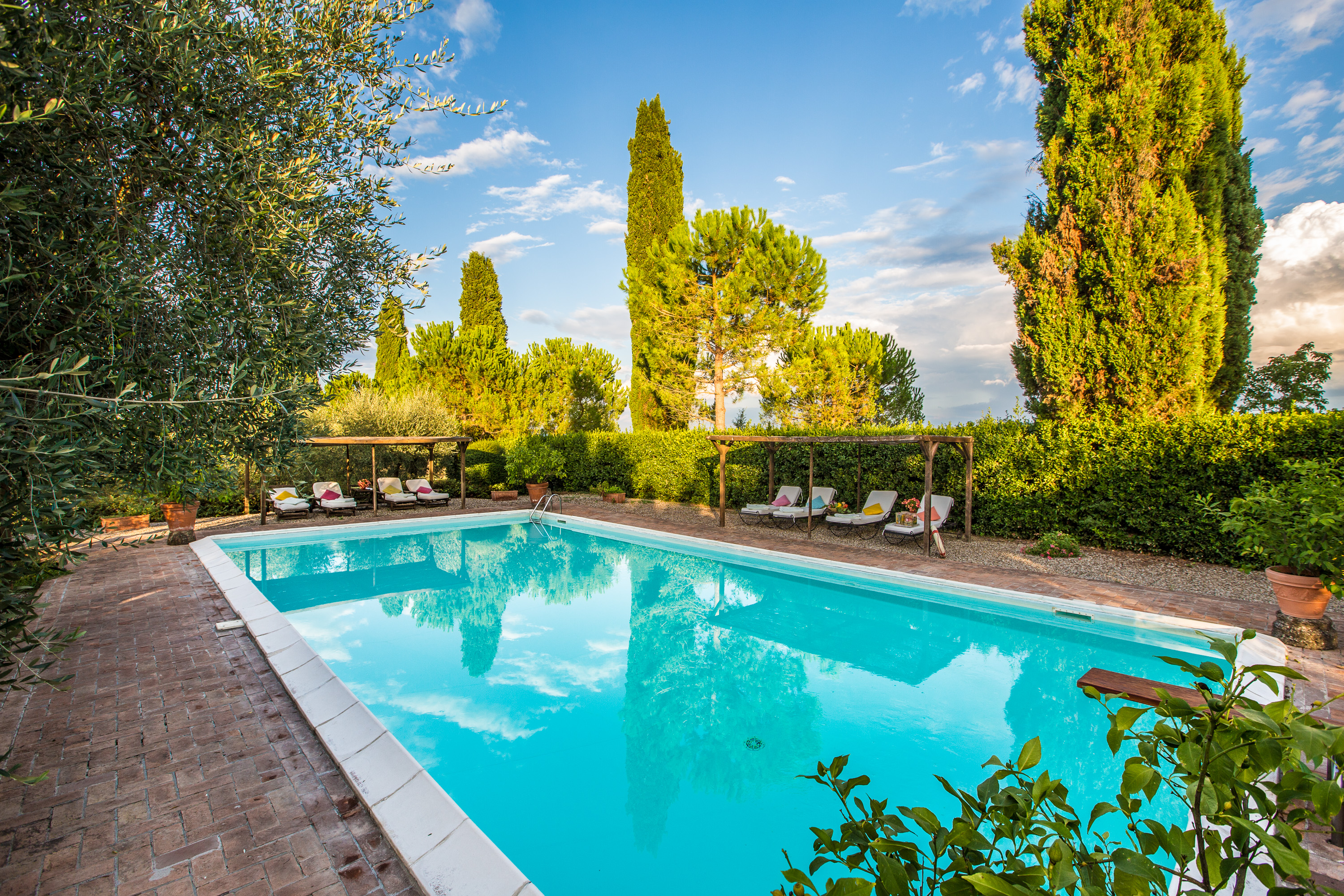 Peaceful swimming pool surrounded by cypress trees at Castello Higo, a luxury yoga and wellness retreat in Tuscany, Italy