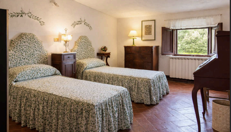 Spacious twin bedroom with rustic Tuscan style and natural light at Castello Higo luxury yoga and wellness retreat