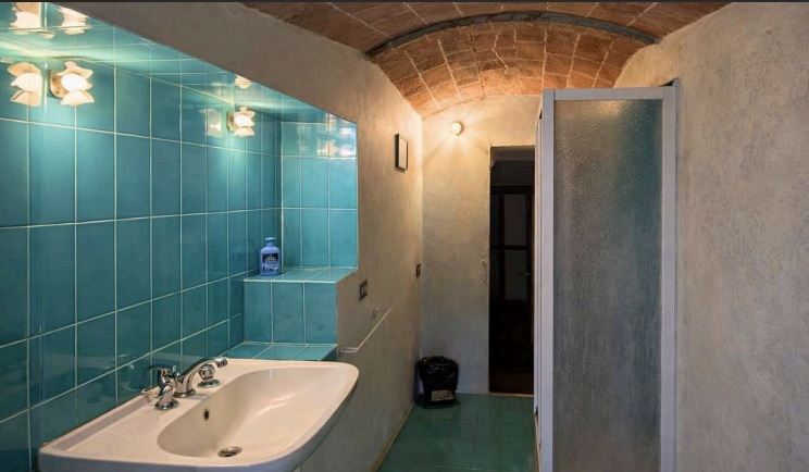 Rustic Tuscan bathroom with stone arches and modern amenities at Castello Higo luxury retreat center in Italy