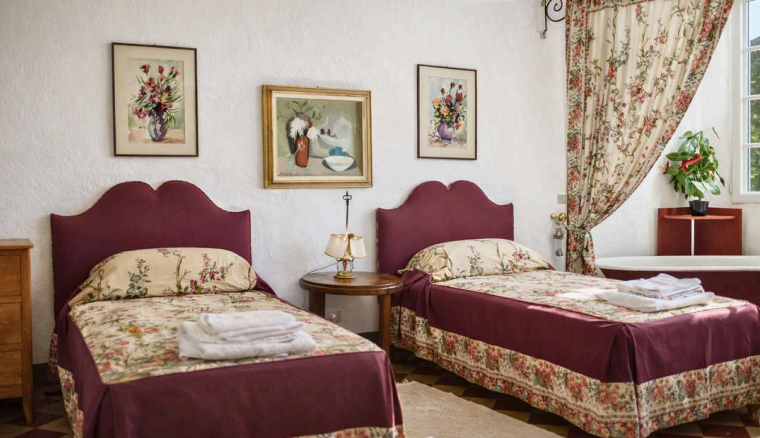 Charming twin bedroom with floral decor at Castello Higo, a luxury yoga and Pilates retreat center in Tuscany, Italy