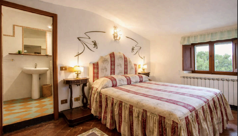 Elegant Tuscan bedroom with handcrafted headboard at Castello Higo, a luxury yoga and Pilates retreat in Tuscany