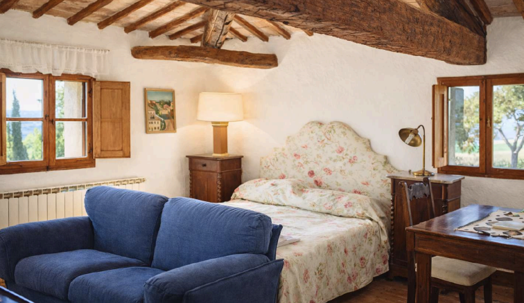 Cozy Tuscan bedroom with rustic wooden beams at Castello Higo, a luxury yoga and Pilates retreat center in Tuscany