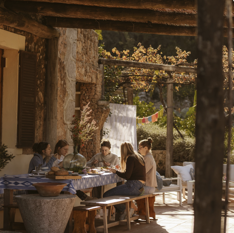 Small group enjoying a meal together outdoors under a shaded terrace roof.