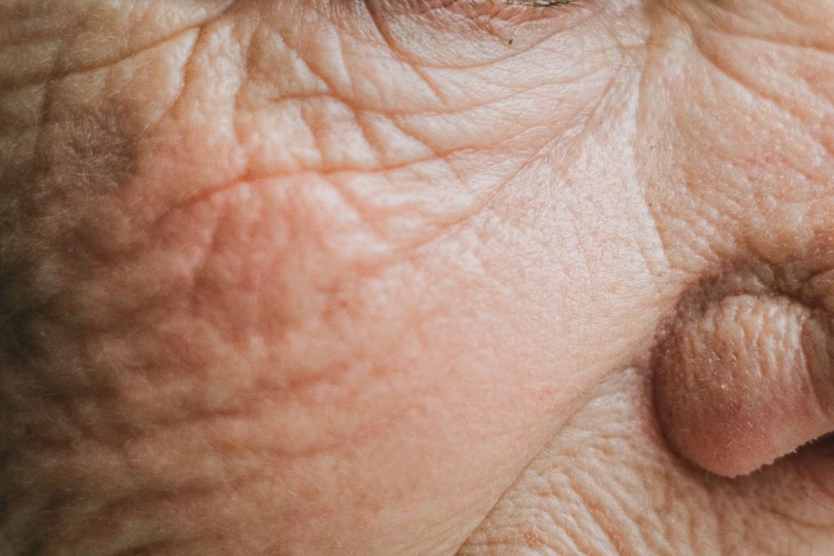 Close-up of a woman's face focusing on her eyes with slightly hooded eyelids and natural eyebrows.