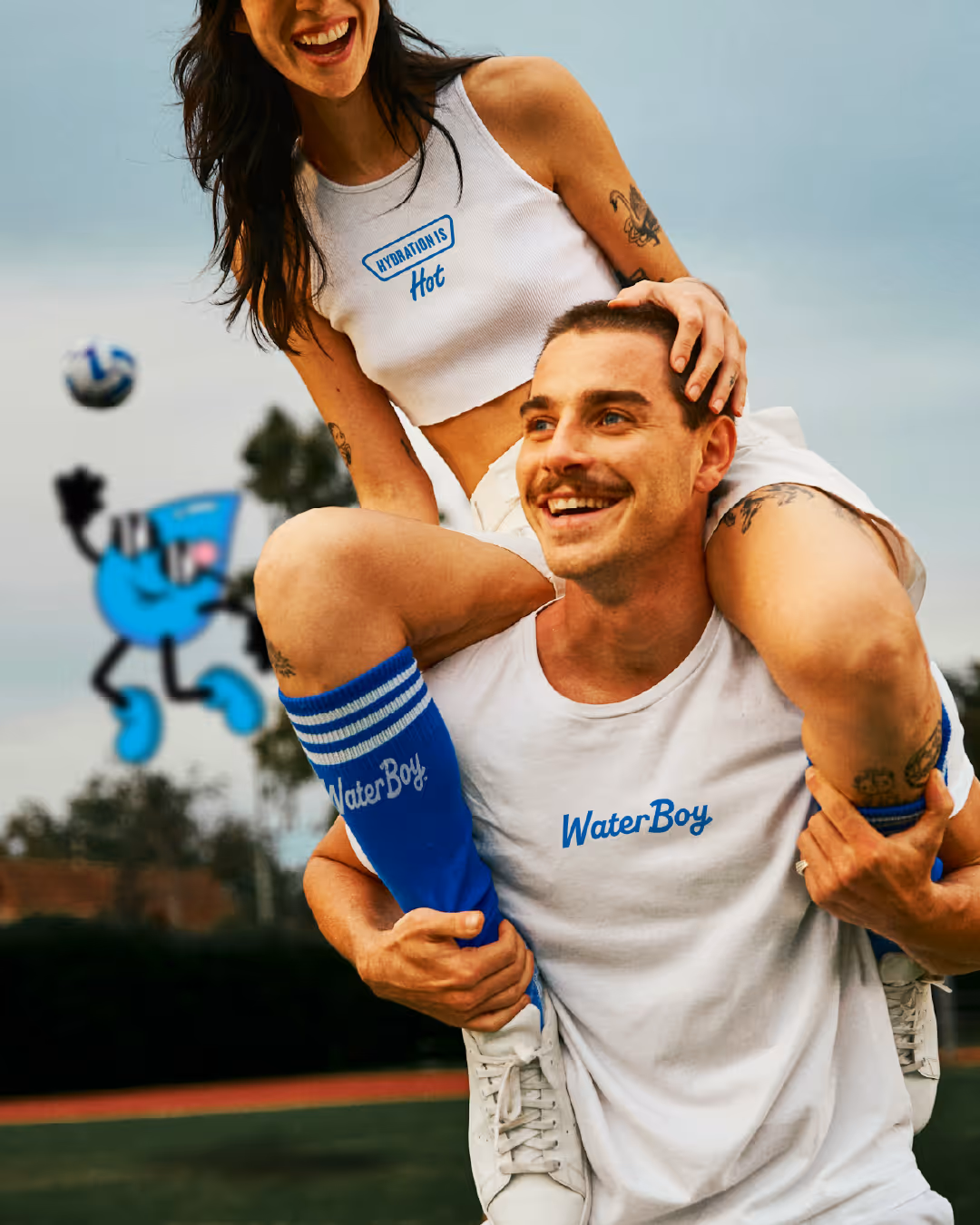 Couple wearing WaterBoy branded apparel — cropped tank, tee, and striped socks — on a sports field.