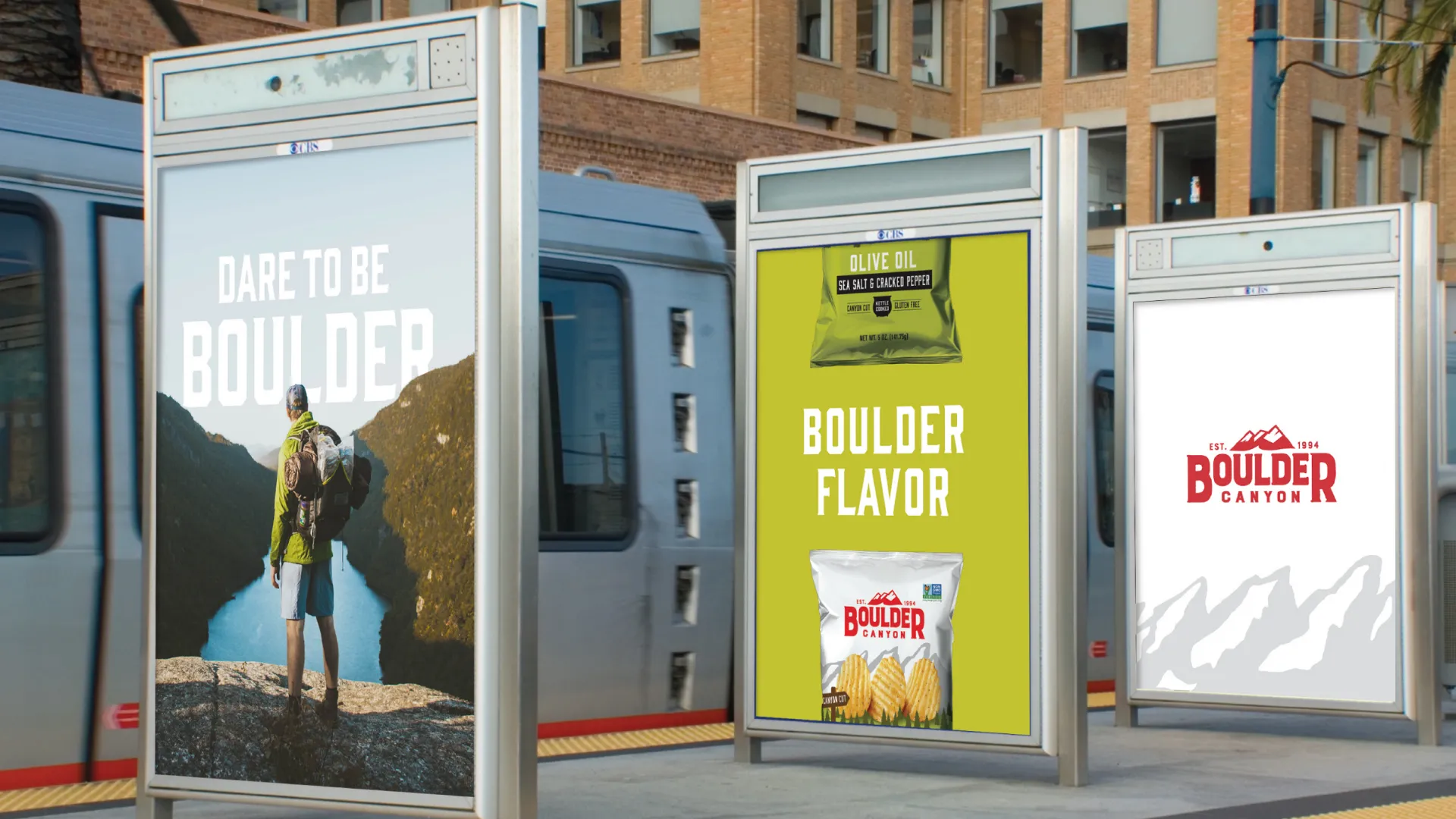 Boulder Canyon transit shelter ads — "Dare To Be Boulder" hiker poster, "Boulder Flavor" bag poster, and logo.