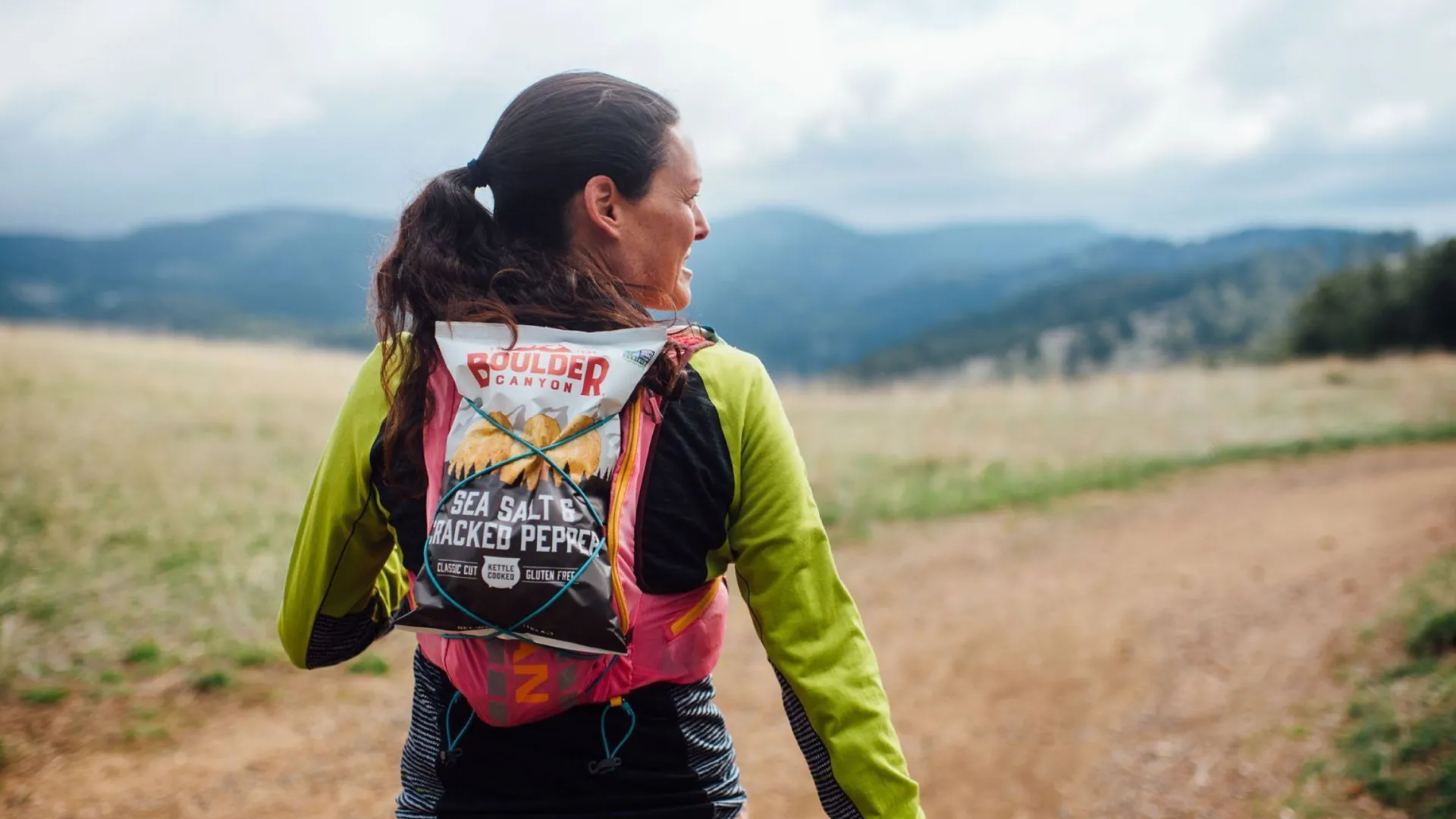 Trail runner with a Boulder Canyon Sea Salt & Cracked Pepper chip bag tucked into a running pack.