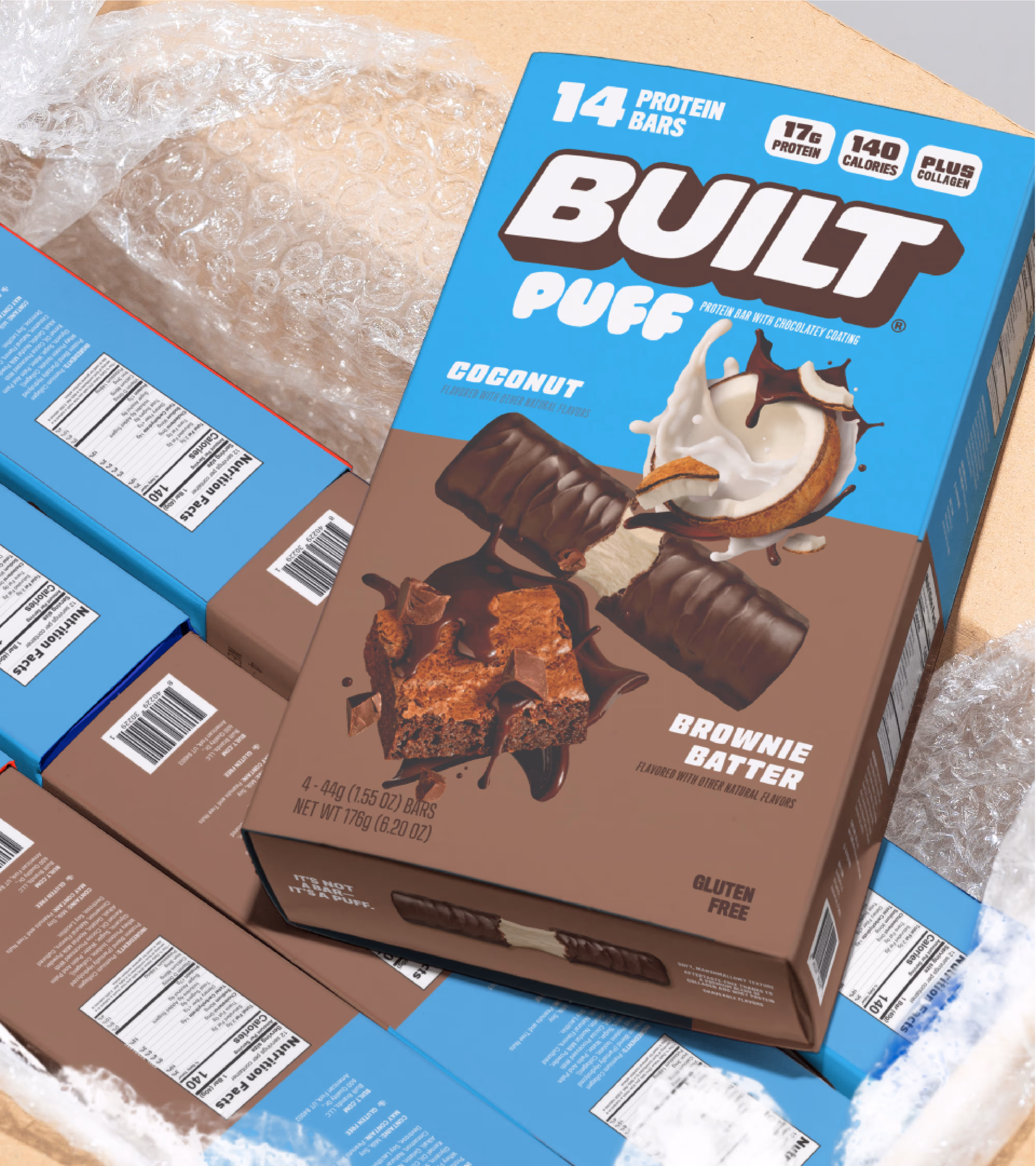 Open shipping carton filled with bubble wrap and Built Puff retail boxes in Coconut and Brownie Batter.