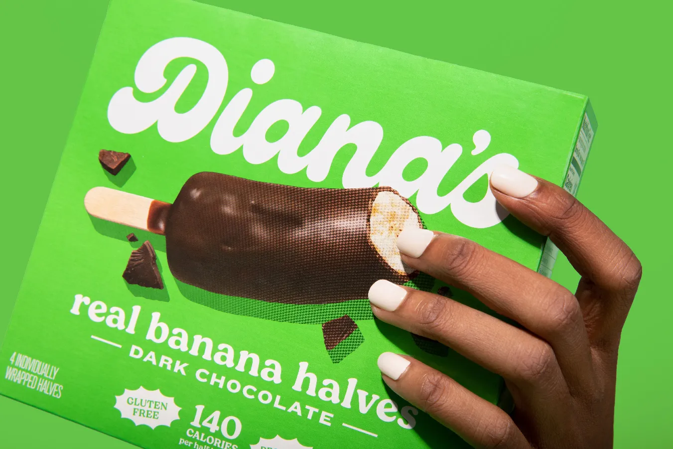 Hand with white nails tilting a green Diana's Dark Chocolate box toward camera.