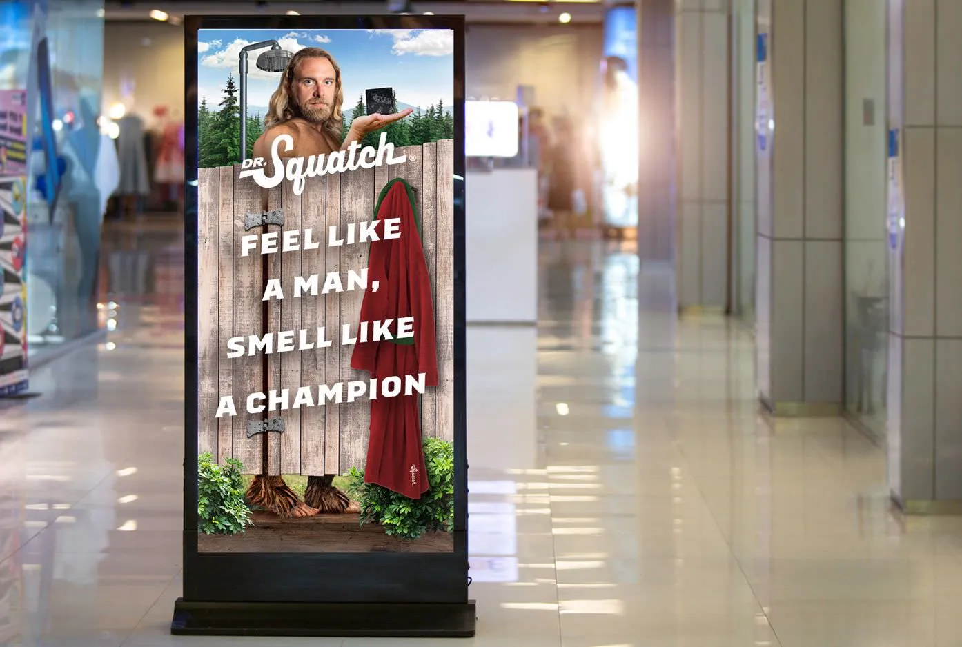 Mall digital sign with a Bigfoot character behind a shower fence; 'Feel like a man, smell like a champion'.