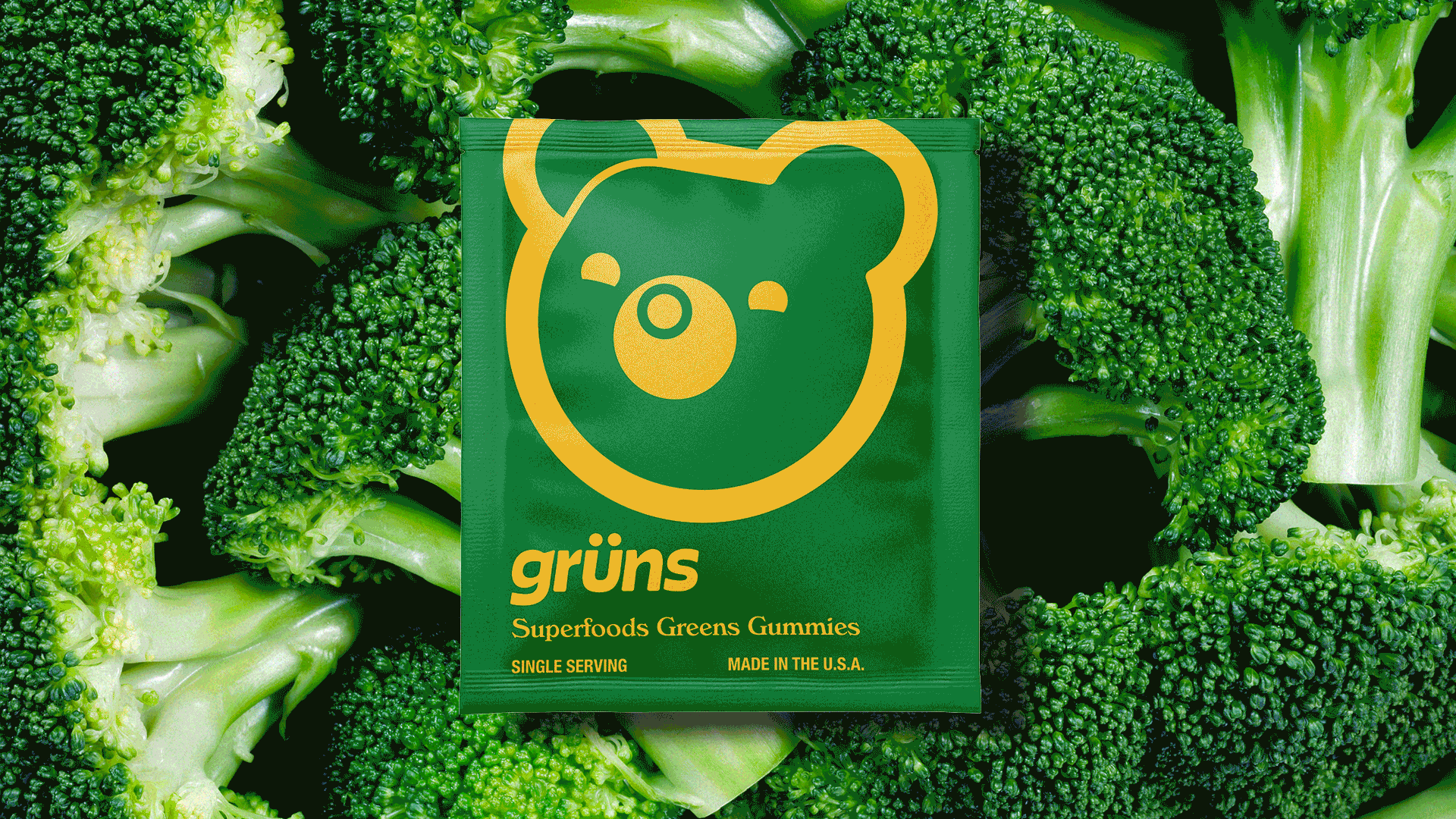 Green Grüns single-serve sachet centered on a top-down broccoli florets background.