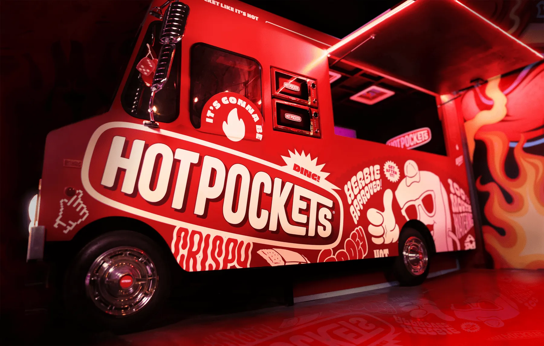 Red Hot Pockets food truck in a dark venue covered in cartoon graphics, mascot art, and 'Crispy / Gooey' lettering.