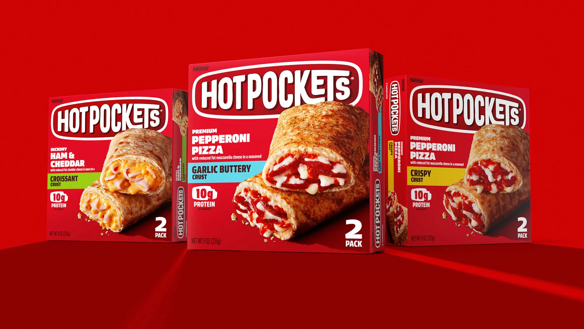 Three Hot Pockets boxes on red: Ham & Cheddar Croissant, Pepperoni Pizza Garlic Buttery Crust, Pepperoni Pizza Crispy Crust.