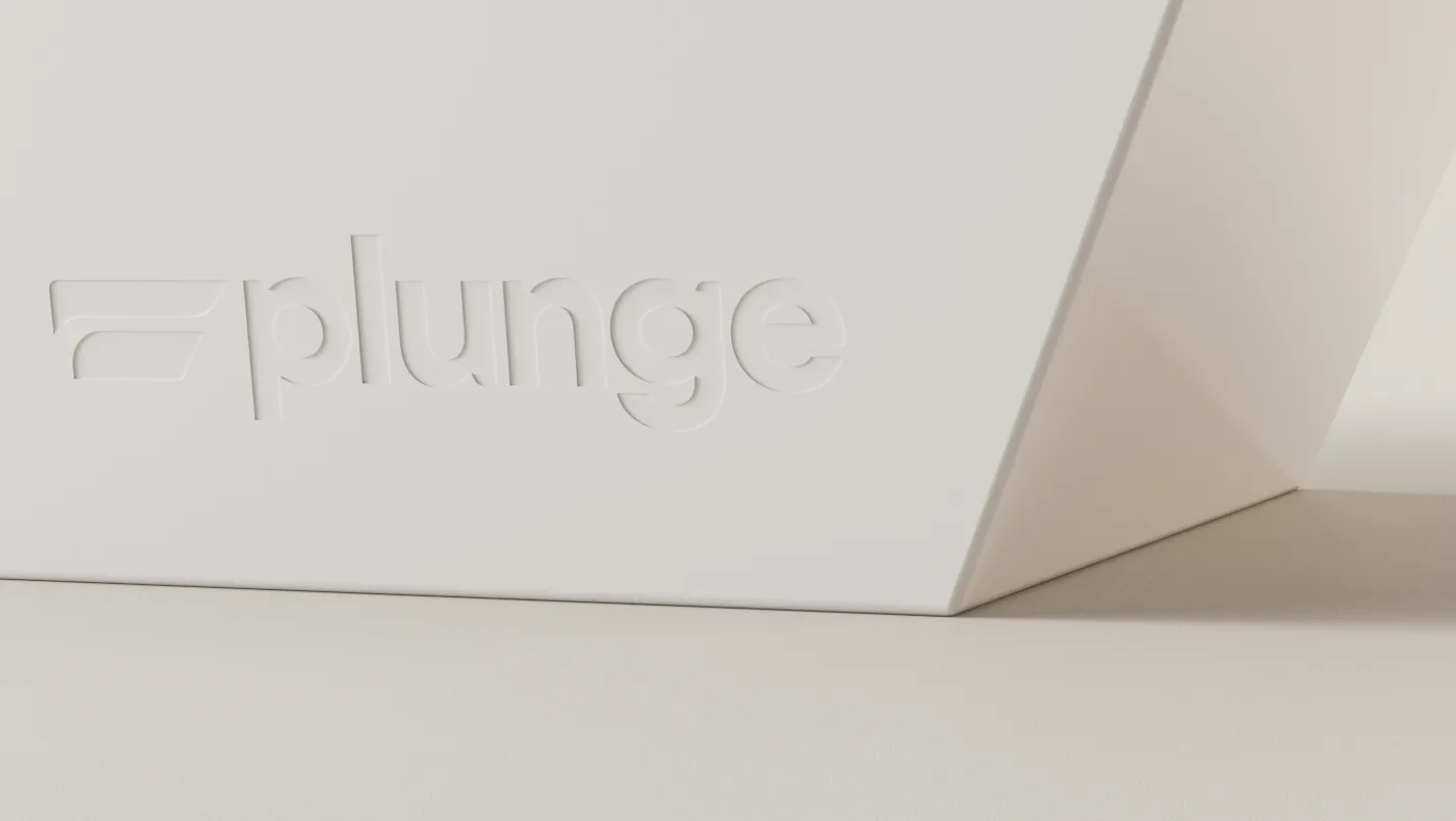 Close-up of a white Plunge tub corner with the wordmark debossed into its angled side panel.