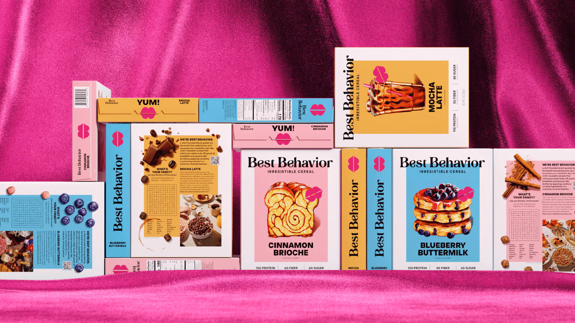 Best Behavior cereal boxes in multiple flavors arranged together on a bright pink satin surface.