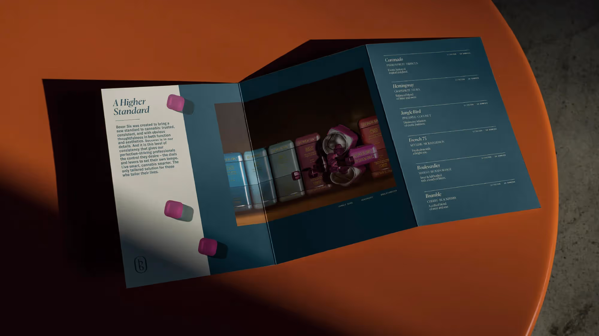 An open Boxer Six brand booklet on an orange surface, showing a flavor menu alongside a product photo.