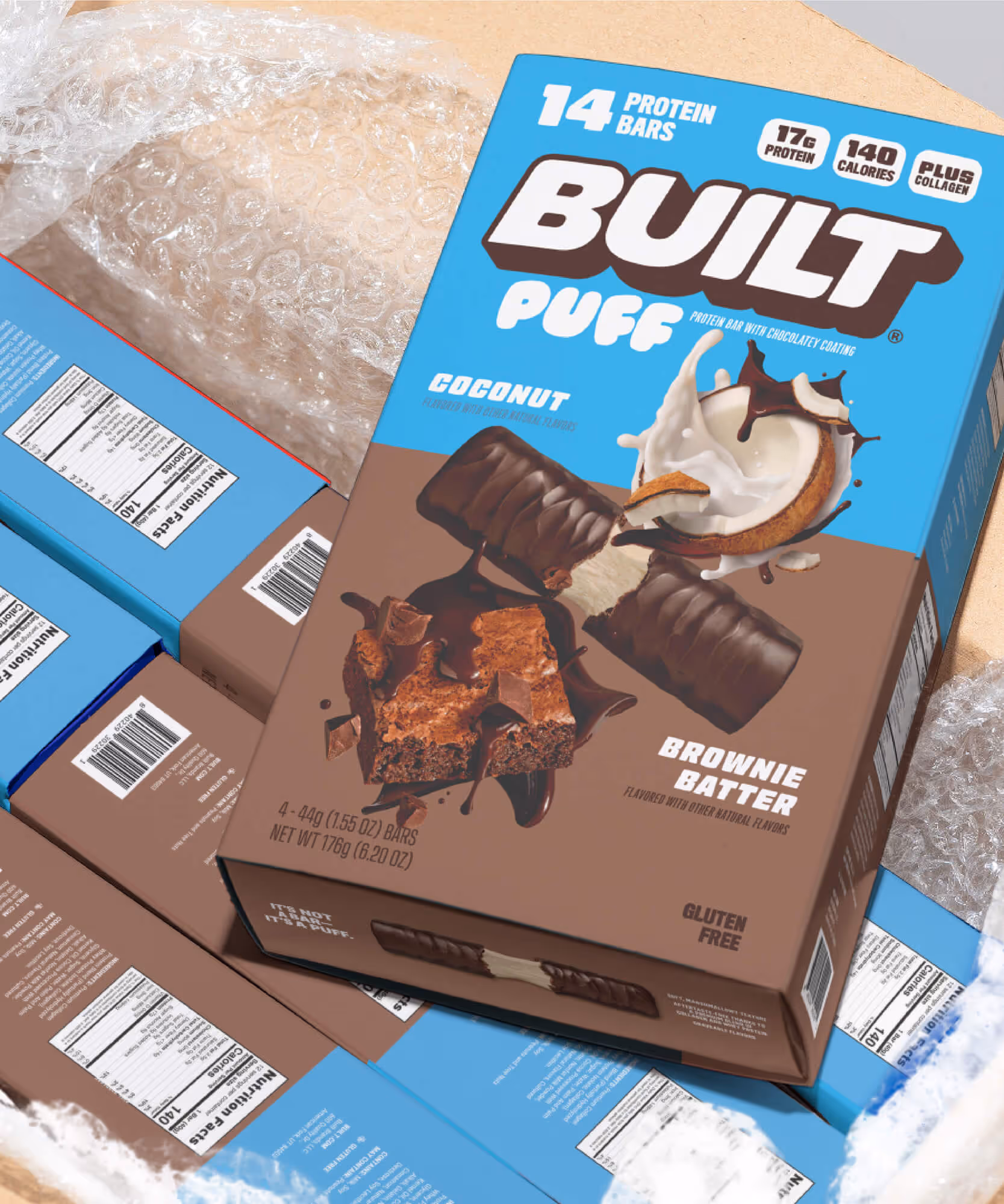 Open shipping carton filled with bubble wrap and Built Puff retail boxes in Coconut and Brownie Batter.